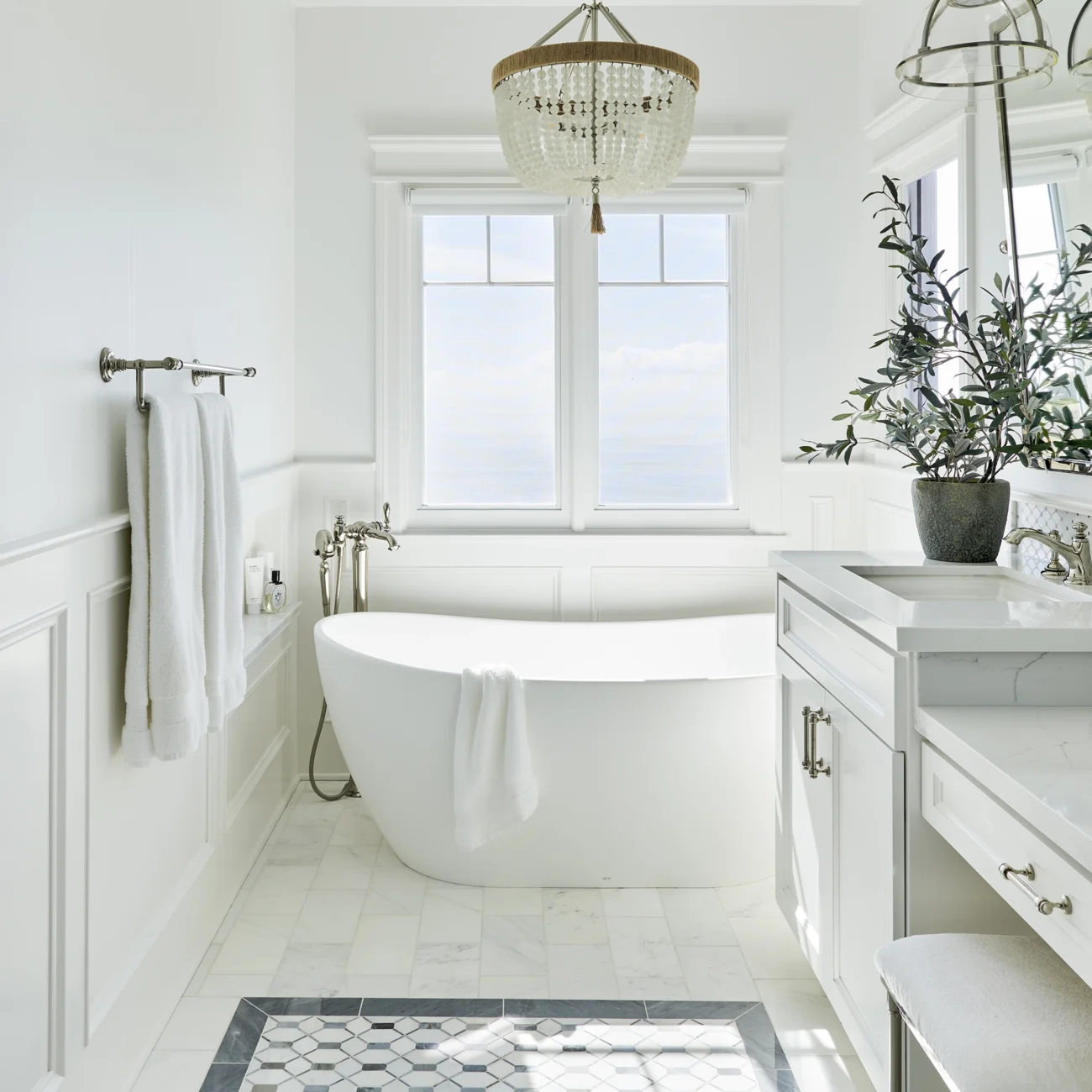 Christine Vroom Interiors Vigilance | Bright white marble bathroom with soaker tub, make-up vanity and chandelier