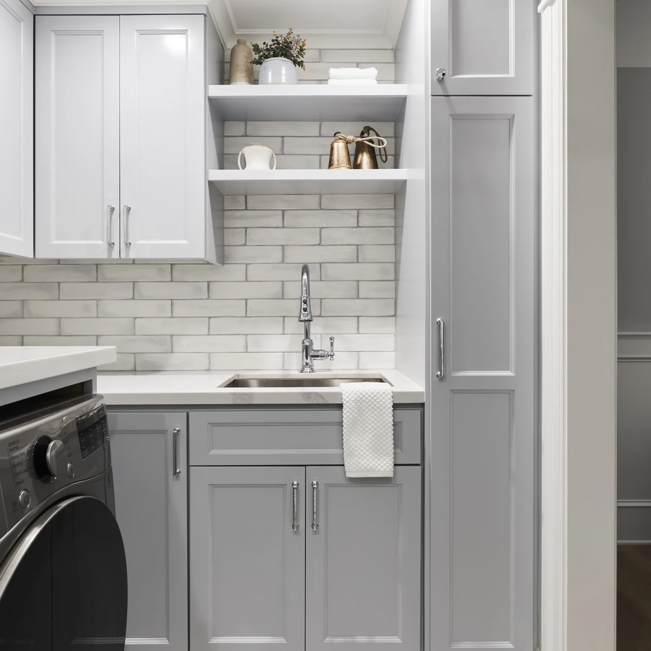 Christine Vroom Interiors Vigilance | Laundry room with light grey cabinets, subway tiles and shelving