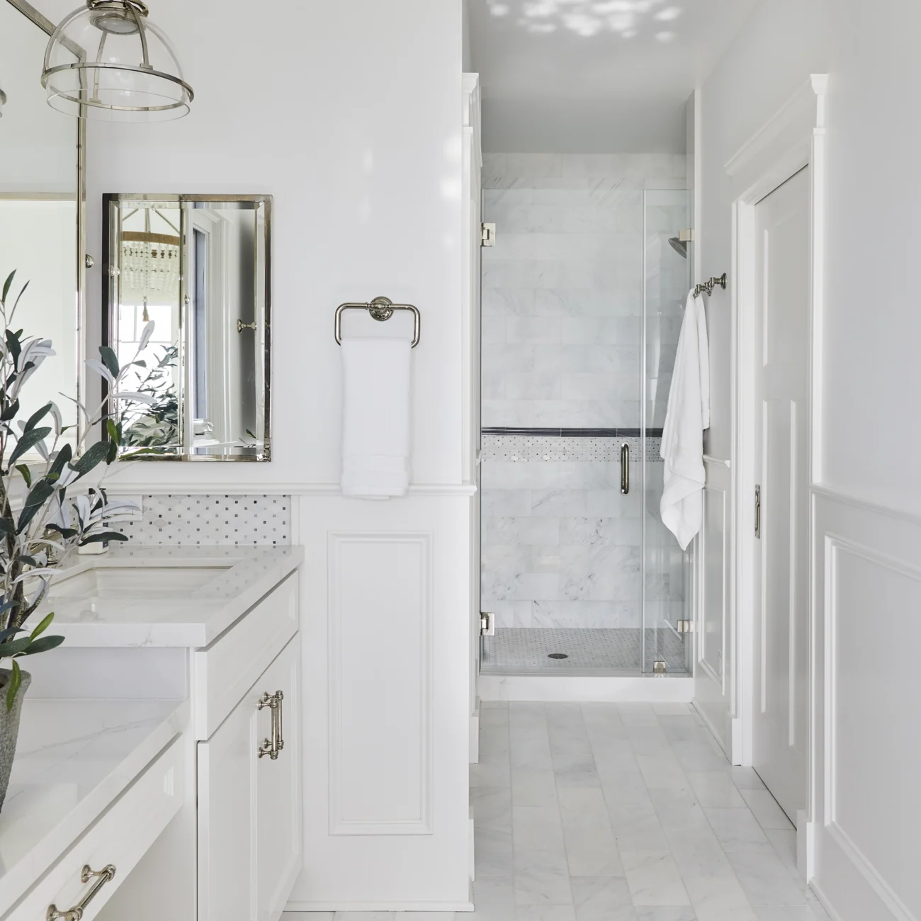 Christine Vroom Interiors Vigilance | Bright white marble bathroom vanity and glass shower