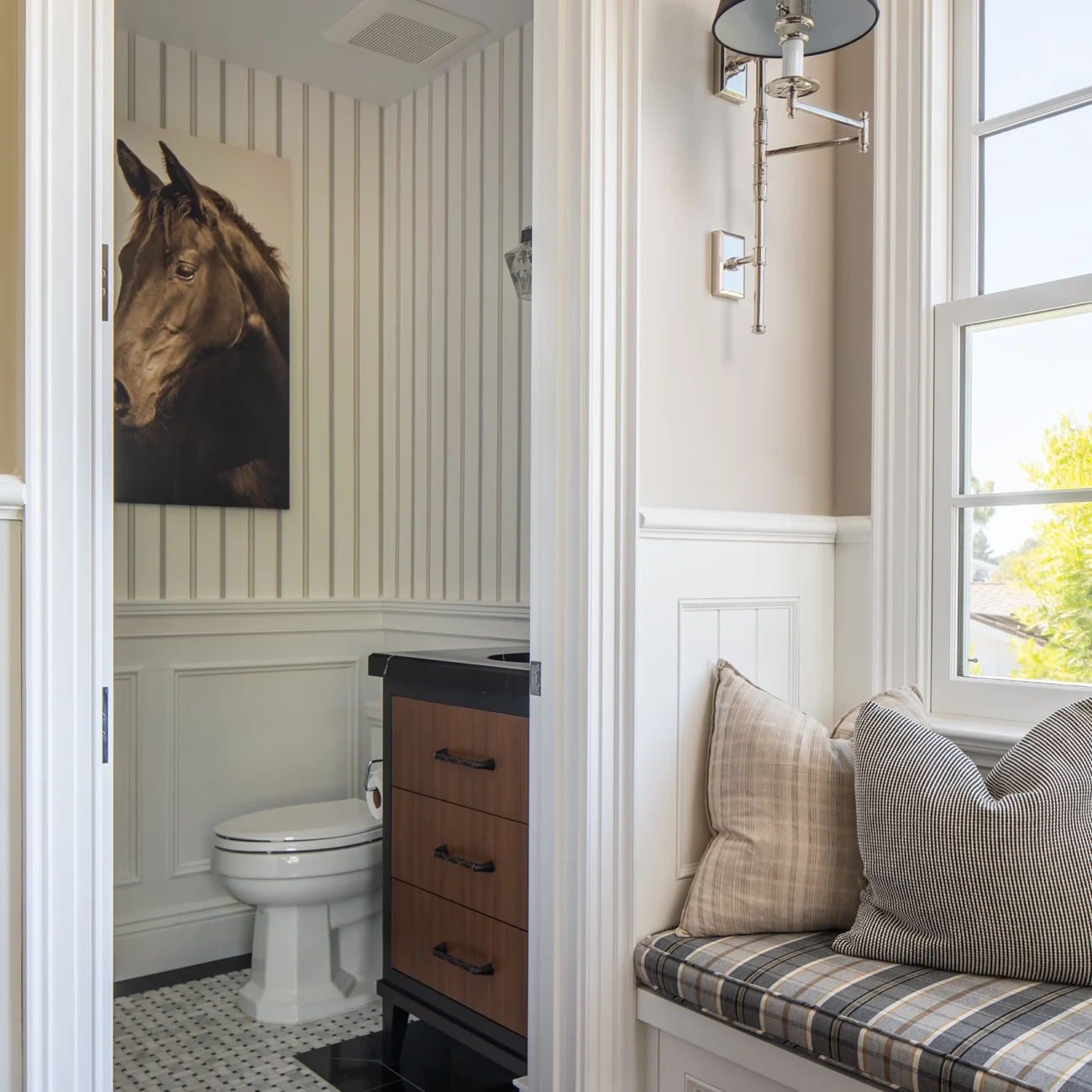 Christine Vroom Interiors Strawberry Lane | Traditional equestrian themed bathroom with black sink and wainscoting and view of seating nook