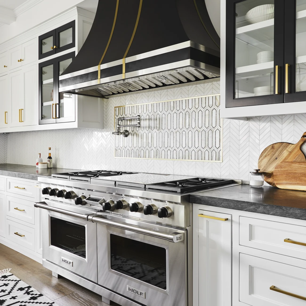 Christine Vroom-Interiors Thayer | Traditional white kitchen with black stove hood, gold accents and chairs