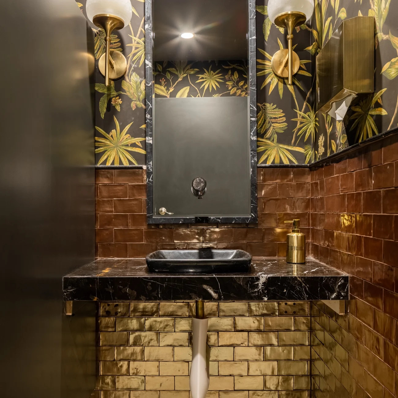 Christine Vroom Interiors Pacific Standard | Contemporary Restaurant Bathroom with black and gold accents and gold metallic subway tiles